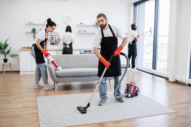 Foto retrato de un limpiador profesional barbudo del servicio de limpieza de alfombras de aspiradoras