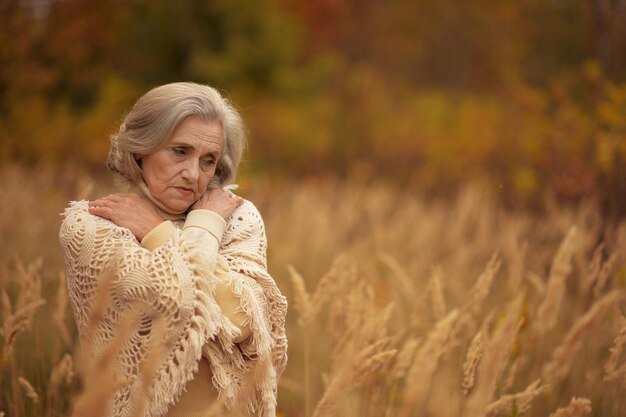 Retrato de linda anciana triste en el parque de otoño