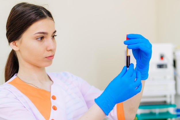 Retrato de una linda asistente de laboratorio analizando una muestra de sangre en el hospital