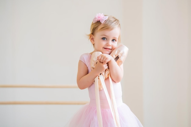 Retrato de una linda bailarina bebé de ojos azules con zapatos de punta rosa