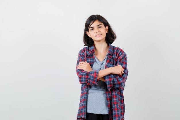 Retrato de linda chica adolescente de pie con los brazos cruzados en camisa a cuadros y mirando orgullosa vista frontal