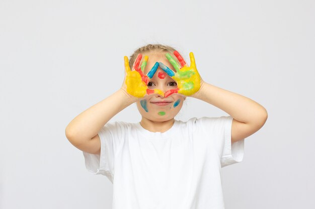 Retrato de una linda chica alegre con manos pintadas, aislado en blanco