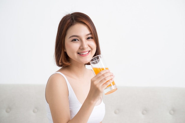 Retrato de una linda chica casual bebiendo jugo de naranja de un vaso