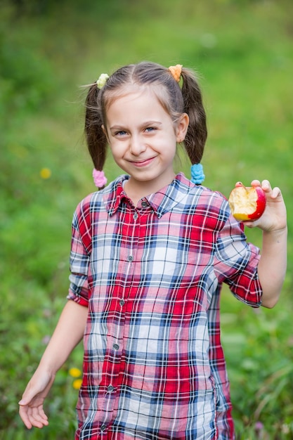 Un retrato de una linda chica comiendo una manzana en un jardín agrícola Cosecha otoñal de manzanas