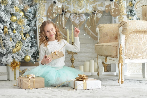 Retrato de linda chica feliz sentada con regalos de Navidad