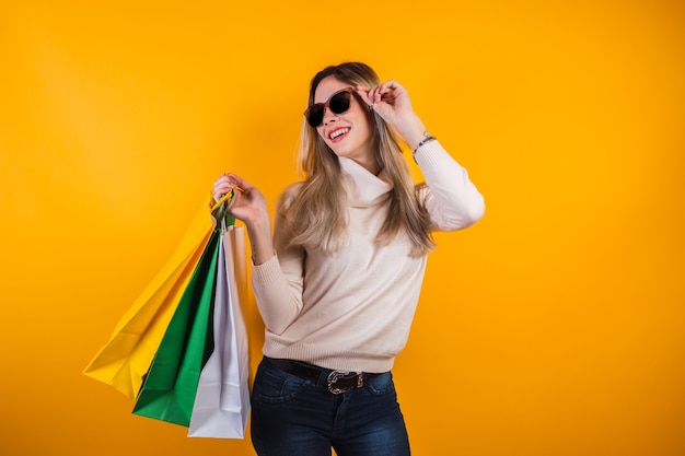 Retrato de linda chica con gafas de sol feliz con bolsas de la compra.