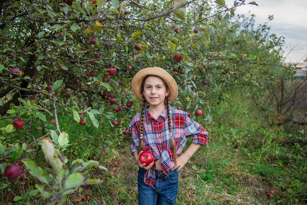 Retrato de una linda chica en un jardín de granja con una manzana roja Cosecha otoñal de manzanas