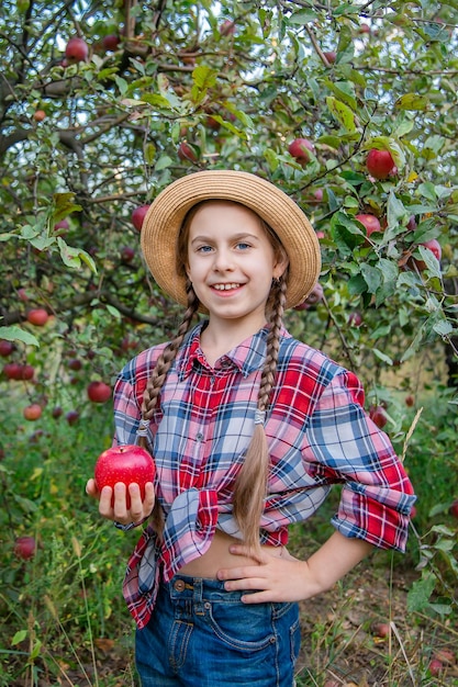 Retrato de una linda chica en un jardín de granja con una manzana roja Cosecha otoñal de manzanas