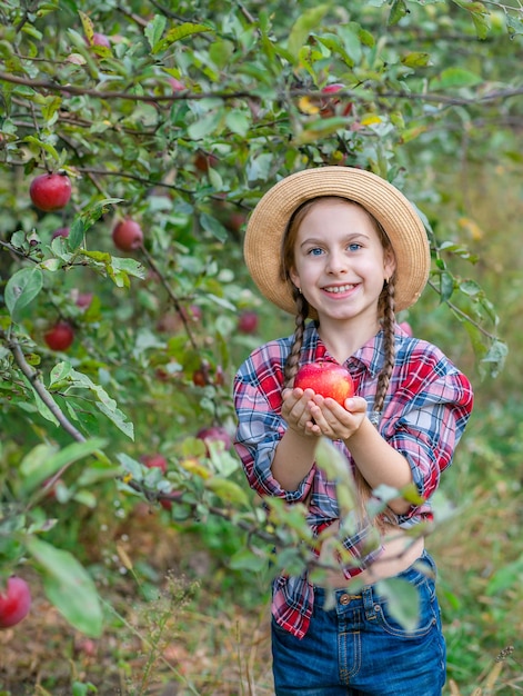 Retrato de una linda chica en un jardín de granja con una manzana roja Cosecha otoñal de manzanas