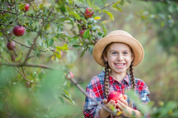 Retrato de una linda chica en un jardín de granja con una manzana roja Cosecha otoñal de manzanas