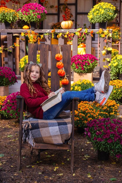 Retrato de una linda chica con un libro en otoño en un banco