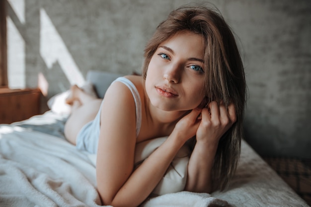 Retrato de linda chica con ojos grandes acostada en la cama