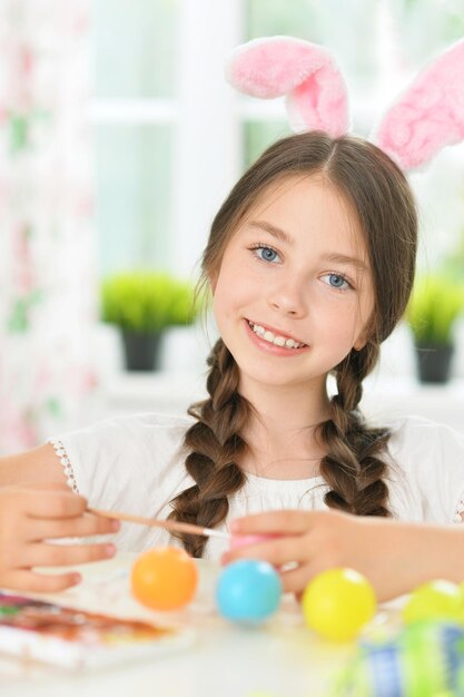 Retrato de una linda chica pintando huevos para las vacaciones de Semana Santa