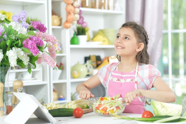 Retrato de linda chica preparando deliciosa ensalada fresca