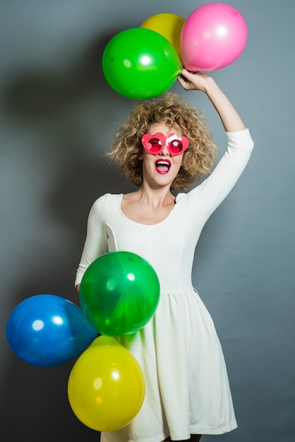 retrato de una linda chica rubia sosteniendo un montón de globos