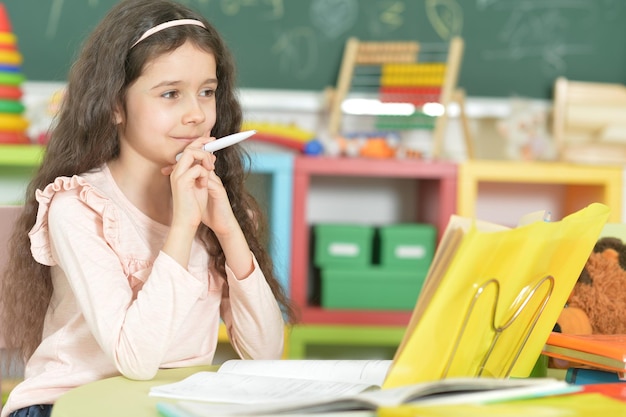 Retrato de linda colegiala haciendo la tarea en el aula