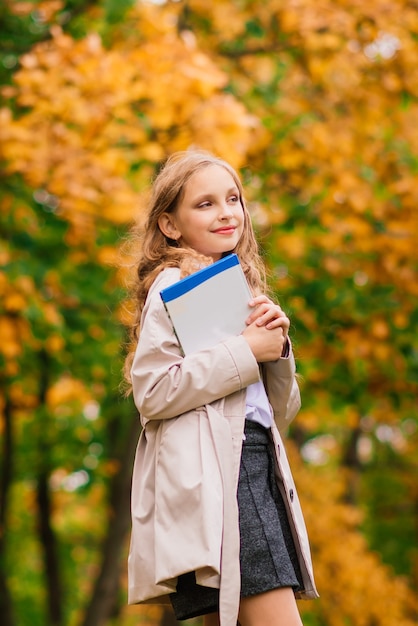 Retrato de una linda colegiala con interesante libro en entorno natural