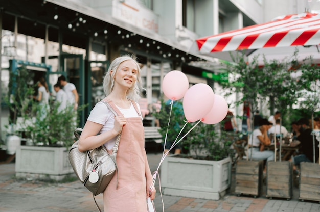 Retrato de una linda dama caminando por la calle con globos