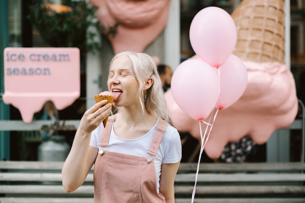 Retrato de una linda dama caminando por la calle con helados y globos