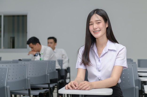 Retrato de linda estudiante asiática con tirantes en los dientes