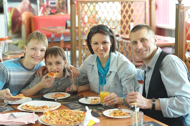 Foto retrato de una linda familia comiendo pizza en el café