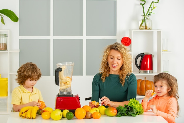 Retrato de linda familia está haciendo jugo de frutas en la cocina blanca