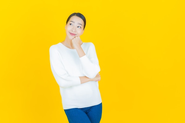 Retrato linda jovem asiática sorrindo com ação em amarelo