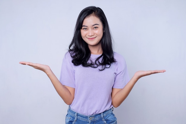 Retrato linda jovem asiática sorrindo com ação, mostrando algo na parede branca