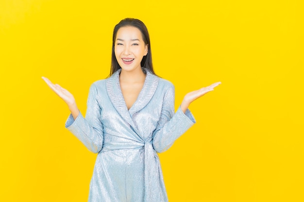 Retrato linda jovem asiática sorrindo com ação na parede amarela