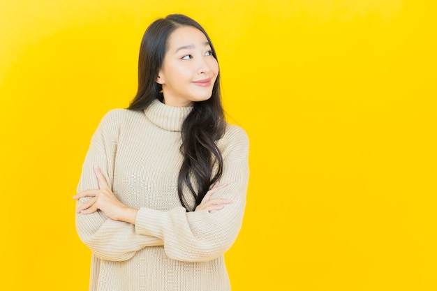 Retrato linda jovem asiática sorrindo com ação na parede amarela