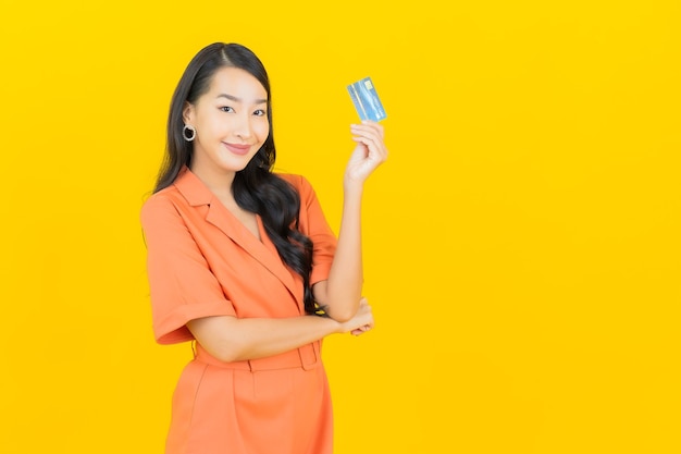 Retrato linda jovem asiática sorrindo com cartão de crédito em amarelo