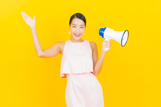 Retrato linda jovem asiática sorrindo com megafone em amarelo