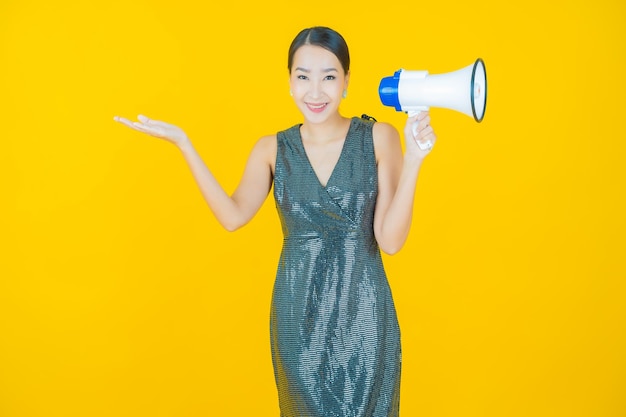 Retrato linda jovem asiática sorrindo com megafone em amarelo