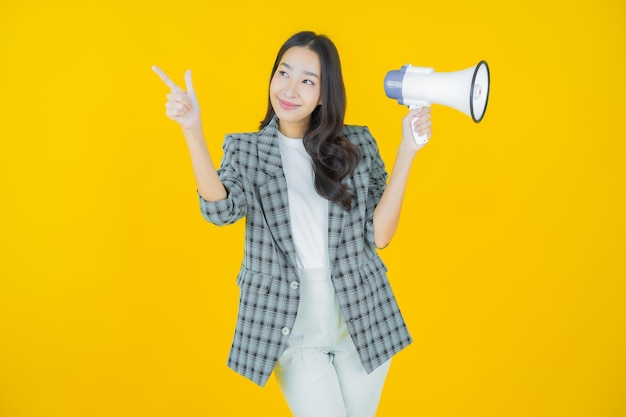 Retrato linda jovem asiática sorrindo com megafone na cor de fundo