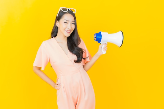 Retrato linda jovem asiática sorrindo com megafone na parede colorida