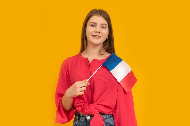 Foto retrato de una linda joven con la bandera de francia en sus manos sobre fondo naranja aprenda la inmigración francesa a francia