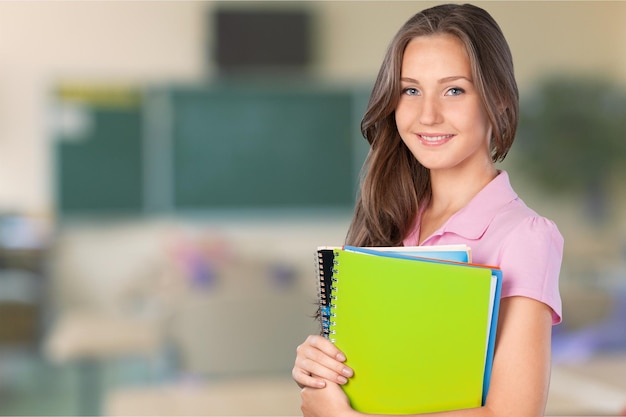 Retrato de una linda joven estudiante sosteniendo cuadernos coloridos