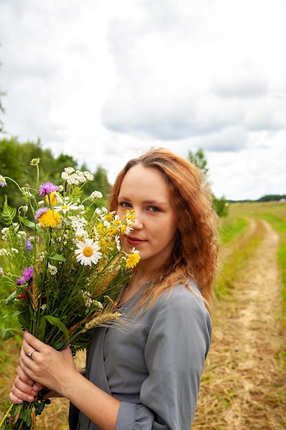 Retrato de una linda joven vestida con flores silvestres en verano