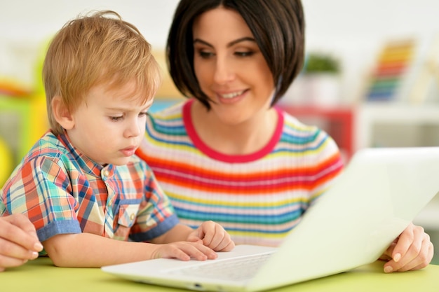 Retrato de linda madre e hijo usando una laptop juntos