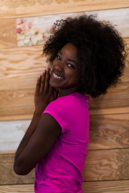 retrato de una linda mujer afroamericana con peinado afro mientras posa contra un viejo fondo de madera retro