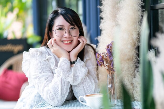 Retrato de una linda mujer asiática feliz y atractiva que huele un ramo de flores púrpuras de lavanda tenía ganas de relajarse en una cafetería como el fondo