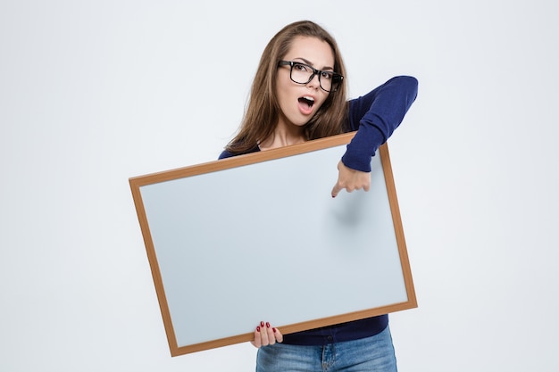 Retrato de una linda mujer hermosa dedo acusador en tablero en blanco aislado en un fondo blanco.