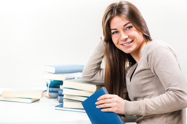 Retrato de linda mujer joven con muchos libros. Mirando a la cámara.