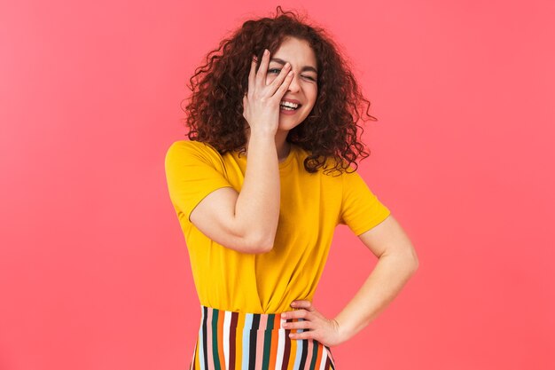 Retrato de una linda mujer rizada joven hermosa posando aislada en la pared roja.