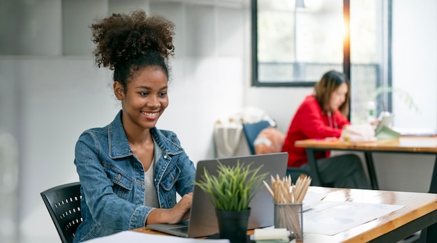 Retrato linda mulher negra sorrindo e usando computador portátil