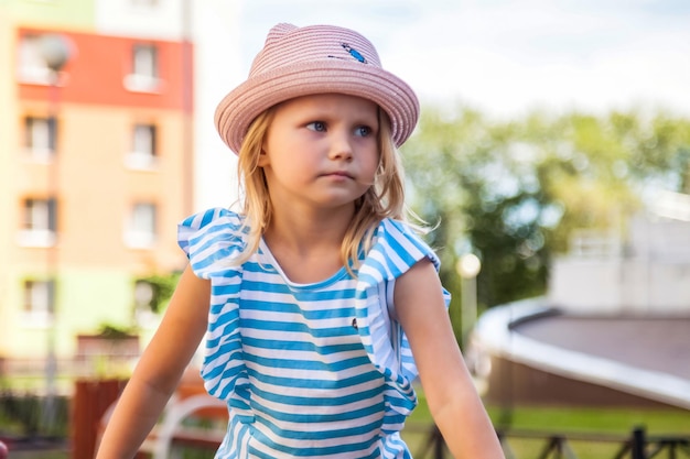 Retrato de una linda niña de 4 años con sombrero de verano en el parque de verano al aire libre mirando hacia otro lado