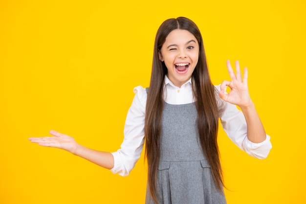 Retrato de una linda niña adolescente señalando con la mano mostrando anuncios con espacio de copia sobre amarillo
