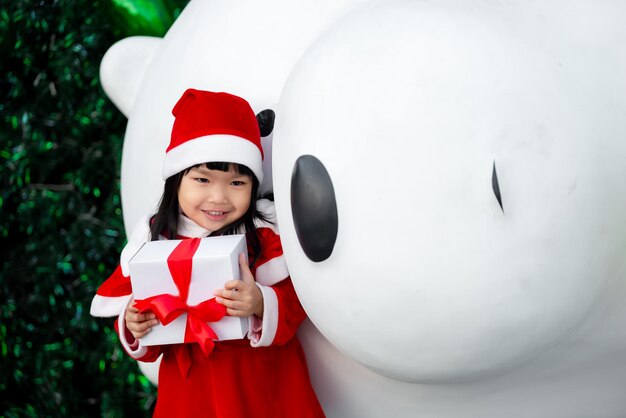 Retrato de una linda niña asiática que usa un vestido de santa feliz cerca del árbol de navidad Niño de Tailandia se une al festival de navidad