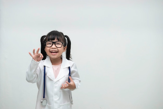 Retrato de linda niña asiática en uniforme médico sobre fondo blanco.