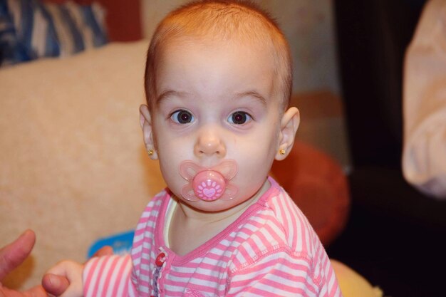 Foto retrato de una linda niña con chupete en casa